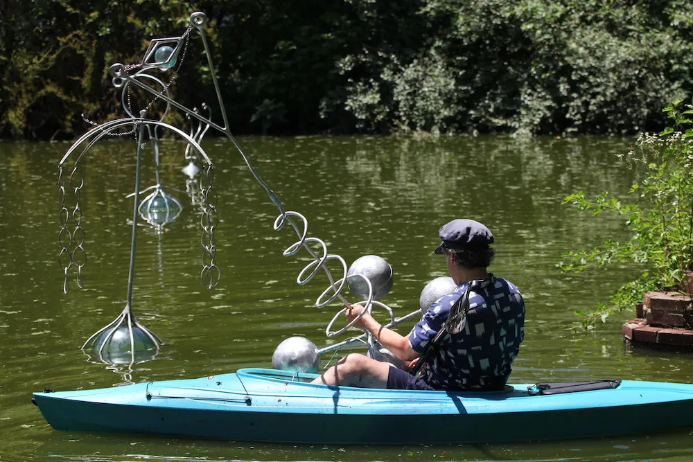 Daniel Rothbart installs his floating sculpture 'Serpentine Sibyls' from a kayak on the pond at Snug Harbor.