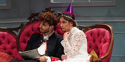 man and woman sitting on velvet couch with cone hats on