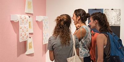 young women looking at paper towel art on pink wall