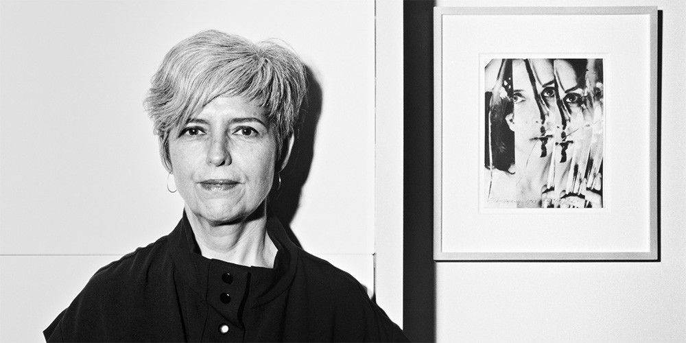 Mónica de la Torre standing next to a photograph