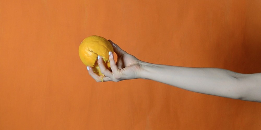 Woman's hand squeezing orange