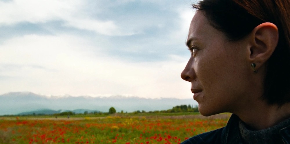 Woman looks back on a field of red flowers. 