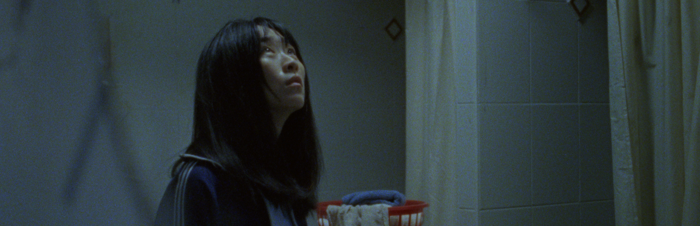 Woman in dimly lit bathroom looking up. 