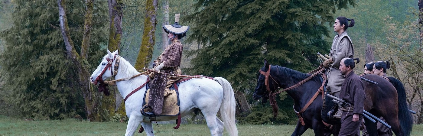 Soldiers riding on horses through a forest. 