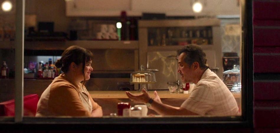 a man and woman sit across from each other at a diner