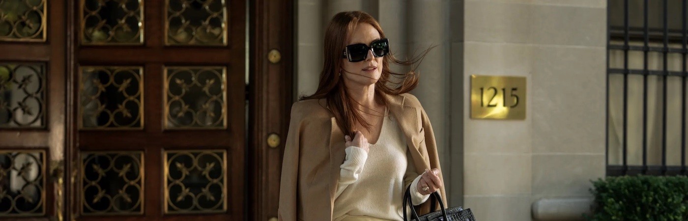 Still from Sharper, a woman in sunglasses exits an apartment building. 