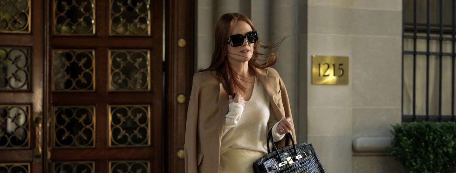 Still from Sharper, a woman in sunglasses exits an apartment building.