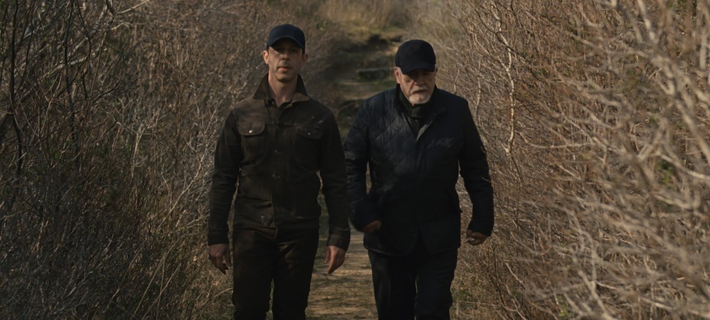 Two men walk in a field. 
