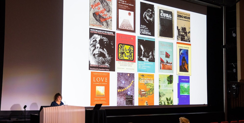 Dean Carol Becker stands at a podium with an image of book covers projected behind her