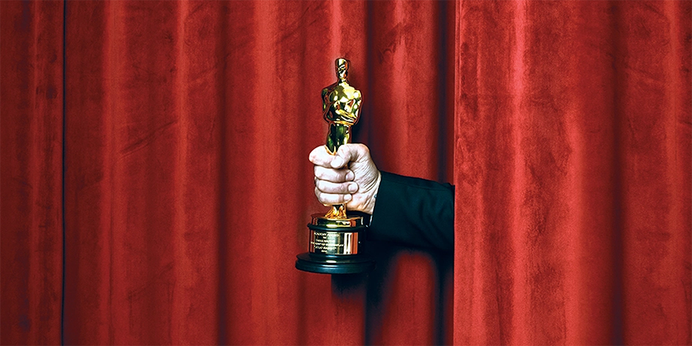 Oscars award statue in front of red velvet curtains.