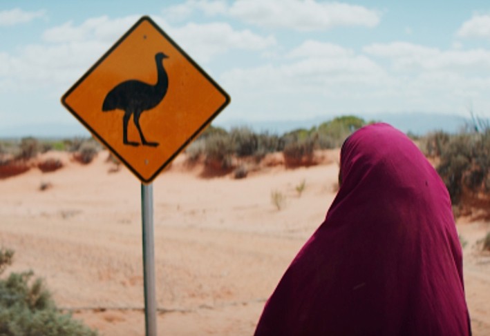 Still from Ayaan written & directed by Alies Sluiter '20, produced by Meng Xiong '19, and associate produced by Federica Belletti '18 Woman in desert looking at a traffic sign indicating ostrich pass.