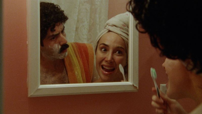 Still from 'Chiqui' man shaving, woman with toothbrush viewed in mirror reflection