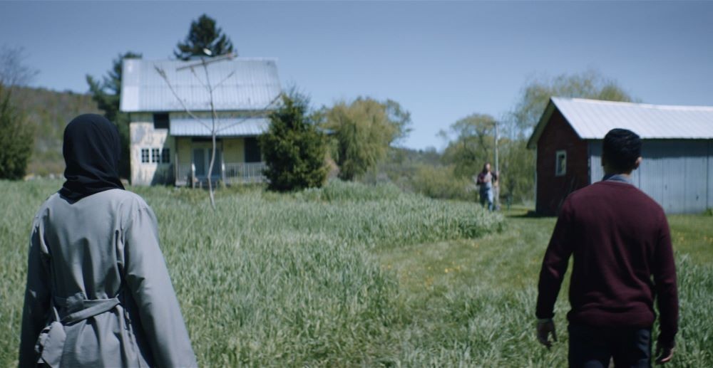 Still from 'The Downpour' Three people in the field of a farm house