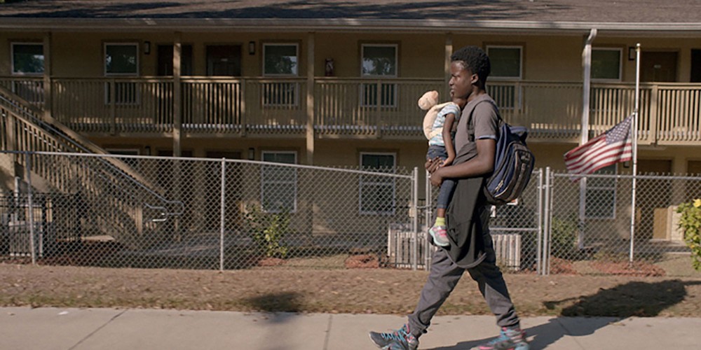Man walking on street holding a child