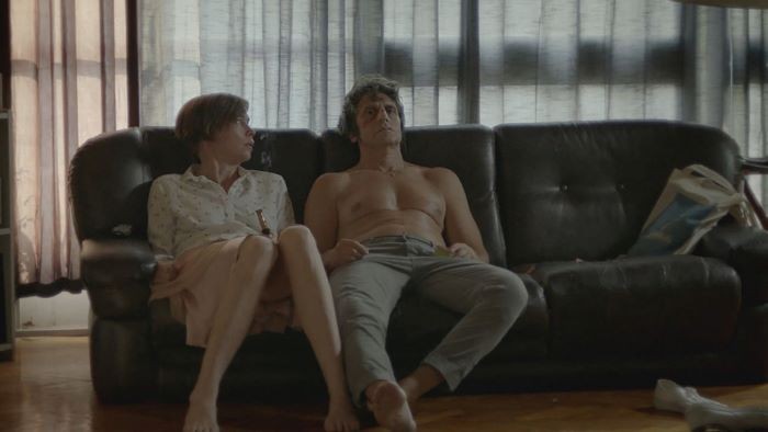 A woman and a man sit on a couch.