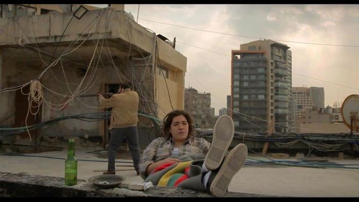 A woman sits on a rooftop.