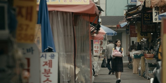 Still from 'House of Hummingbird,' a young woman walks in the streets of South Korea.