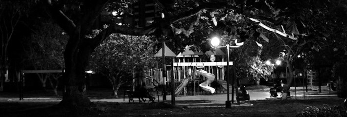 Black and white film still of a playground and tree at night