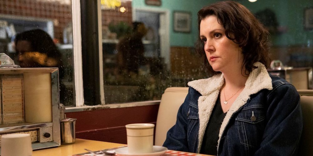 A woman sits in a diner booth.