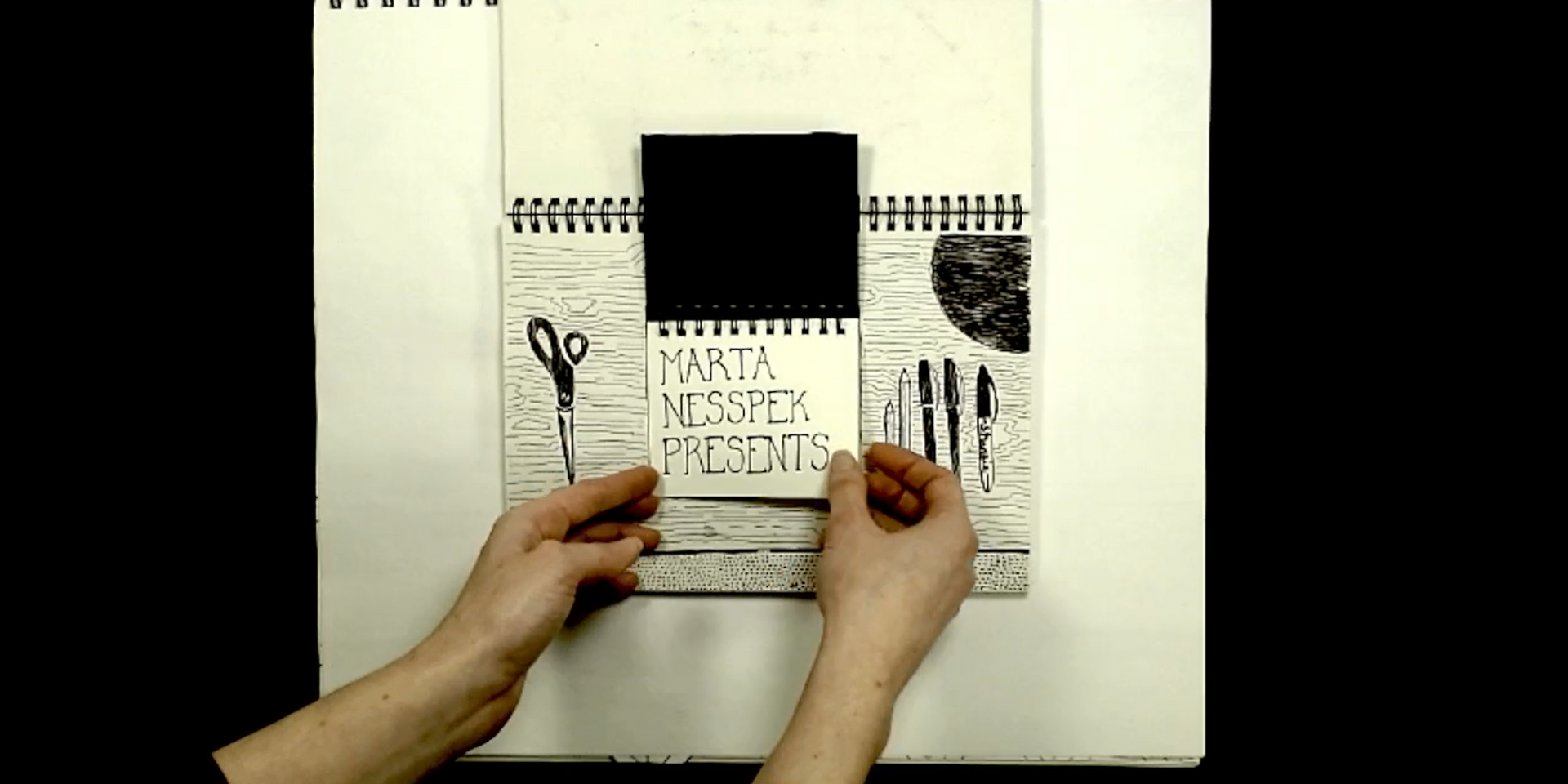 Image of a hand over a drawing that reads 'Marta Nesspek Presents'