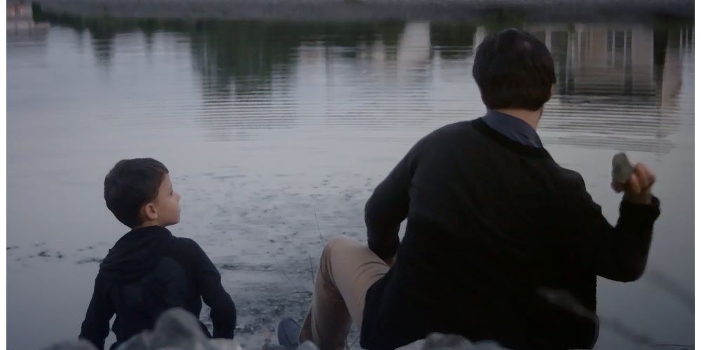 Still from 'Father,' a film by Columbia alumni. A child looks at an older man throwing a rock into a lake.