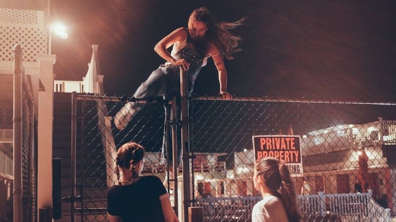 Teenagers climbing fence at night