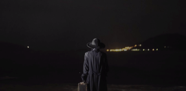 Person in sunhat looking at a lighted bridge in the distance