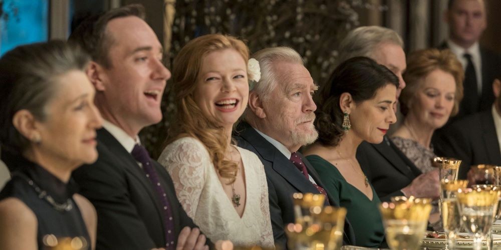 Still from 'Succession' group of people in evening wear at a table laughing