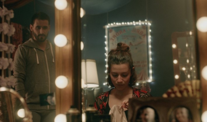 A woman in front of a mirror being looked at by a man.