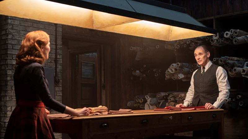 Still from 'The Outfit' two characters looking at each other from opposite ends of a table