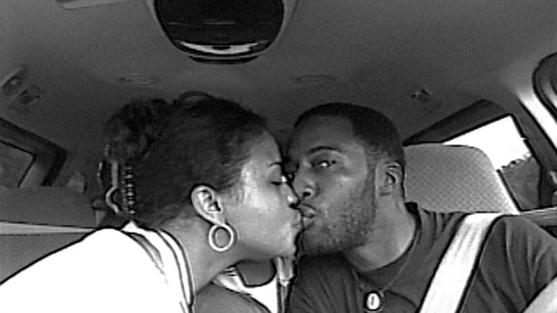 Two people kissing in the front seat of a car