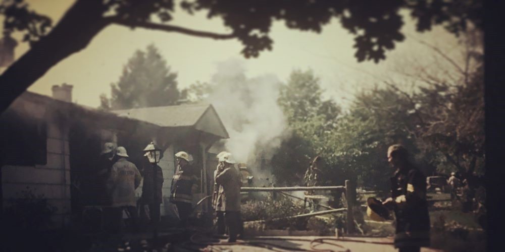 Blurry photograph of firefighters outside a smoking house. 