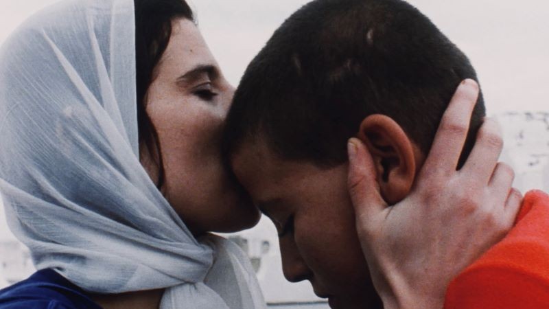 woman with kerchief kissing a boy's head