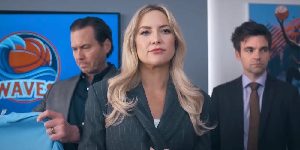 Blond woman stands in front of two men. 