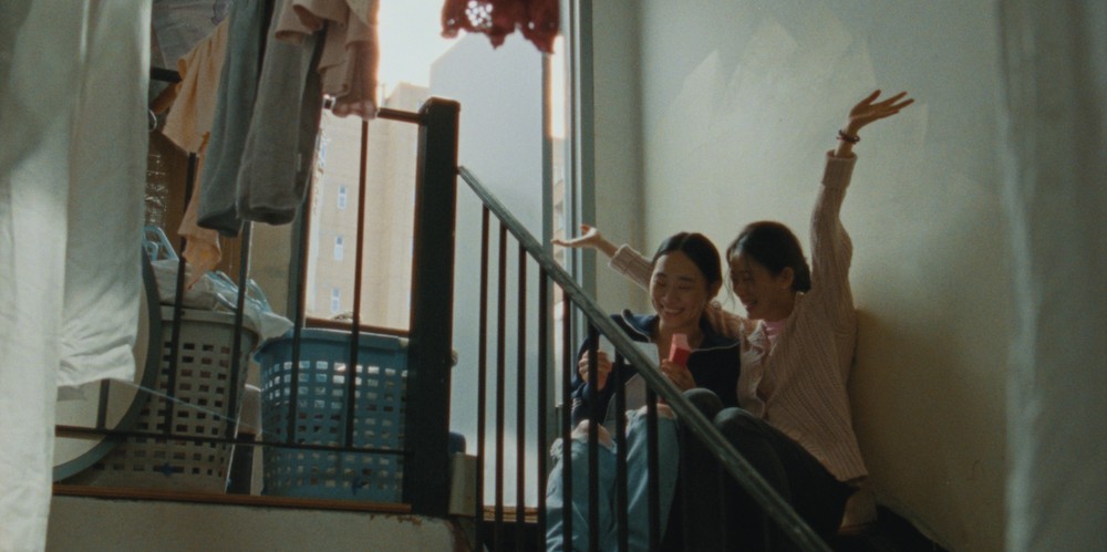 Two girls sit in stairwell. 