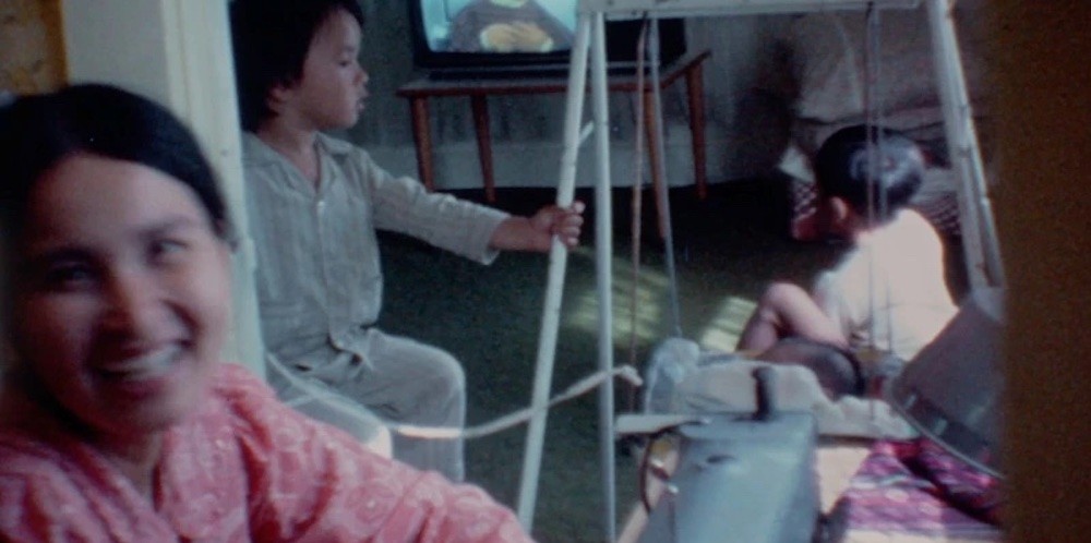 Still of home video footage showing a woman and two young boys. 