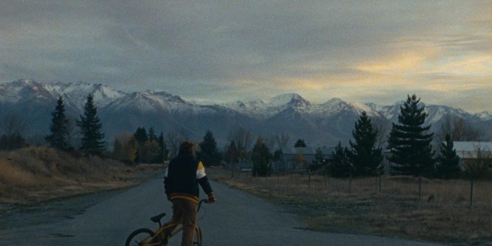 Person on bike rides towards mountain range.