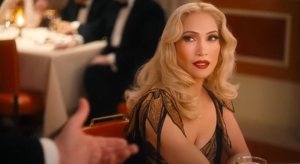 Blond women looks suspiciously at an outreach arm in a black suit. 