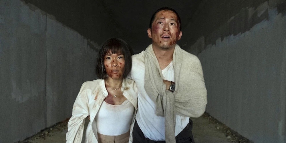 Two bloodied people stand in a tunnel. 
