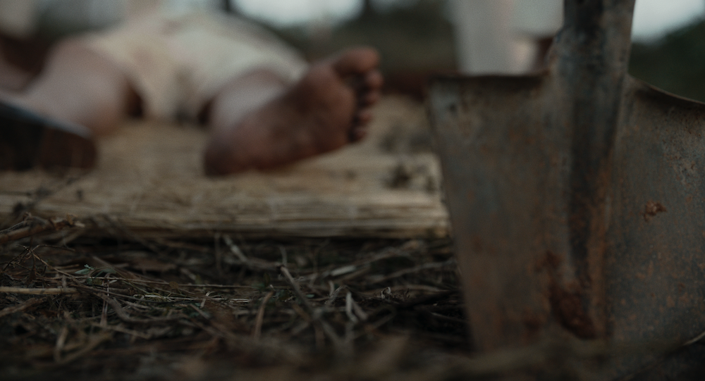 A close shot of a bare foot and shovel