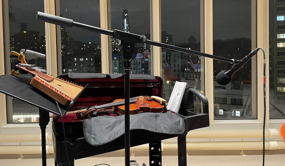 A close-up image of a violin, a microphone, and various other pieces of equipment