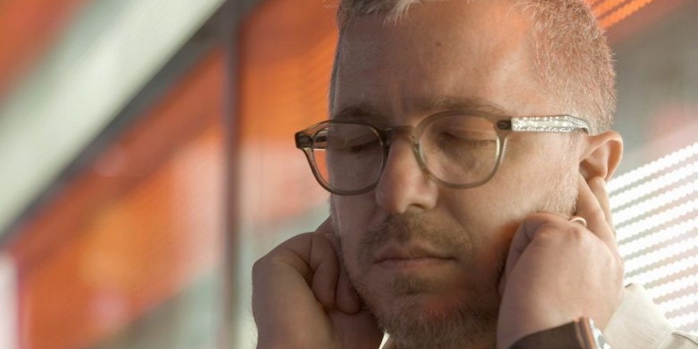 Man with closed eyes plugs his ears with his fingers. 