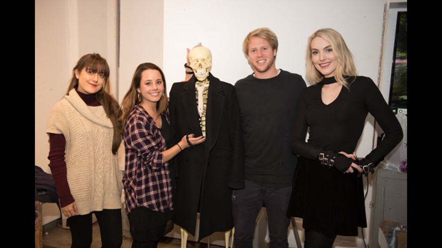 Four students at an event posing with a fake skeleton.