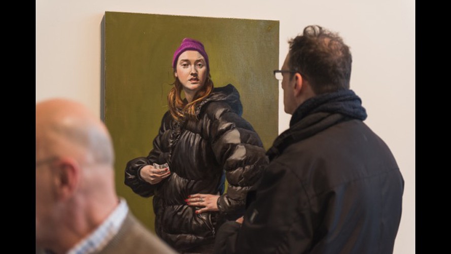 A man looking at a painting of a woman with a puffer jacket.