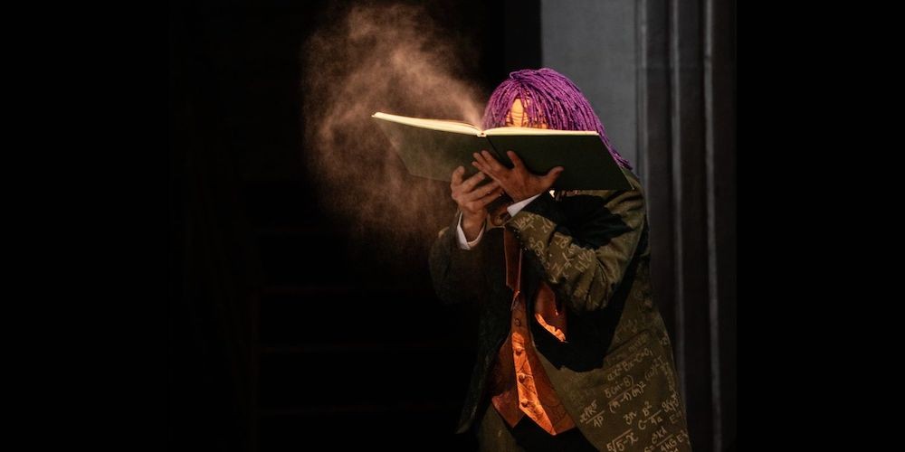 Actor holds book on stage.