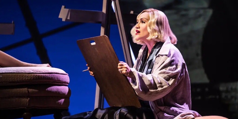 A woman on stage holding an artist's drafting board
