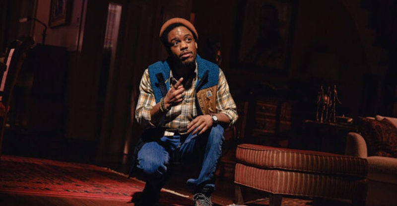 Actor crouches on stage. 