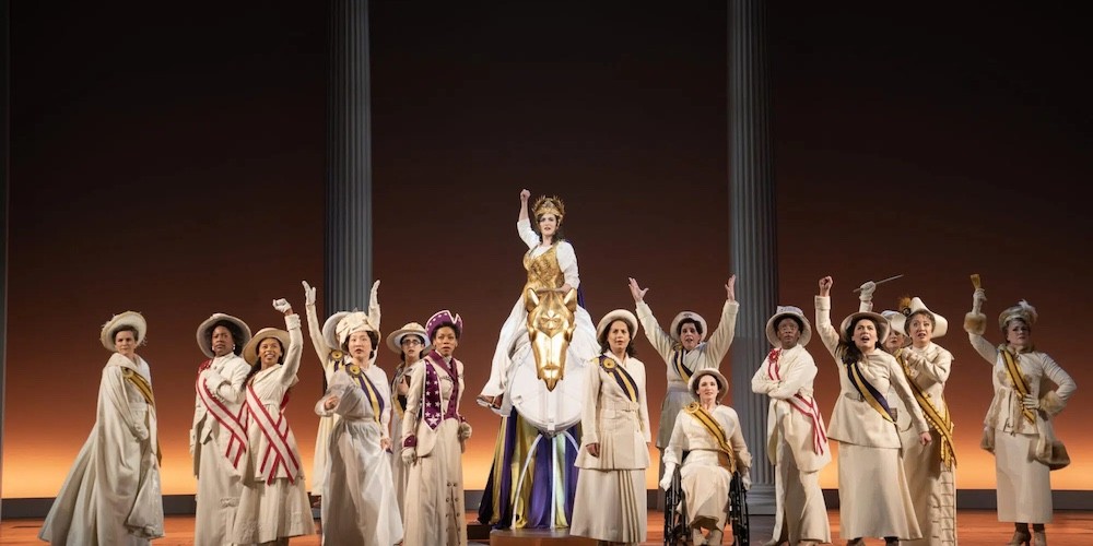 Women in white triumphantly cheers on a stage. 