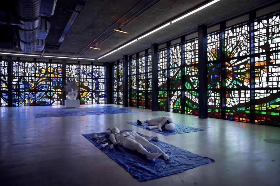 room with stained glass windows and posed statues on floor
