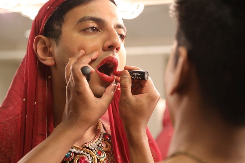 Still from 'Who Killed Taniya' of lipstick being applied to one person by another